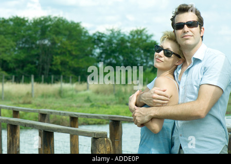 Couple standing par passerelle, man holding femme dans ses bras, tous deux portant des lunettes de soleil Banque D'Images