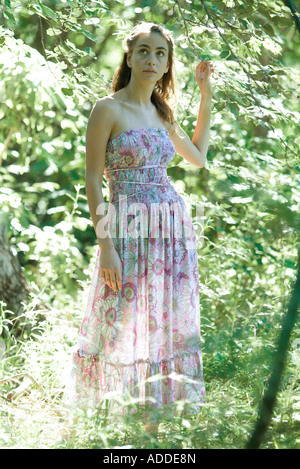 Jeune femme portant robe, standing in woods Banque D'Images