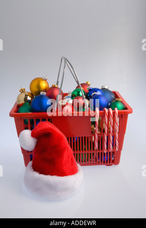 Panier rempli d'arbres de Noël ornements colorés de l'ampoule des cannes de bonbon et santa hat on white background studio portrait Banque D'Images