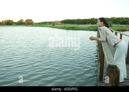 Femme debout sur la passerelle en bois sur le lac, à la distance en Banque D'Images