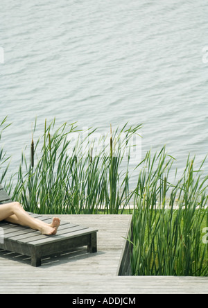 Young woman lying on lounge chair, portrait de jambes Banque D'Images