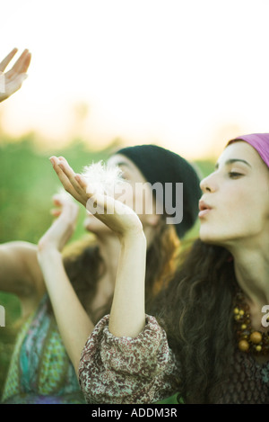 Les jeunes femmes hippie blowing dandelion seeds Banque D'Images