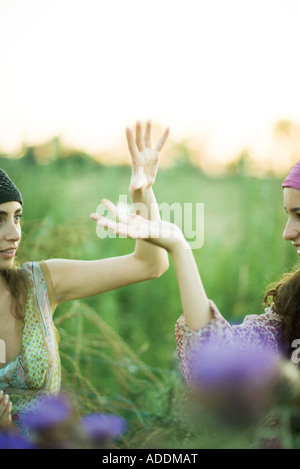 Les jeunes femmes hippie, mains en l'attrapant graines de pissenlit Banque D'Images