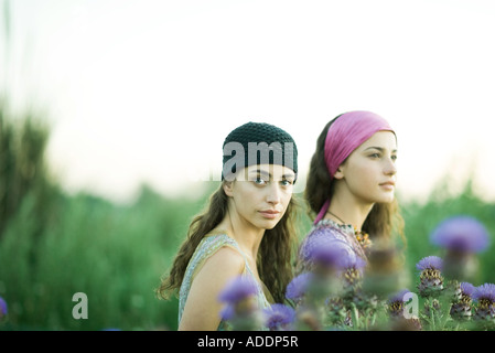 Les jeunes femmes standing in field, le thistle en premier plan Banque D'Images