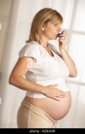 Jolie JEUNE FEMME ENCEINTE EN BONNE SANTÉ EN UTILISANT L'ASTHME INHALATEUR Banque D'Images