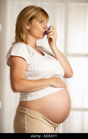 Jolie JEUNE FEMME ENCEINTE EN BONNE SANTÉ EN UTILISANT L'ASTHME INHALATEUR Banque D'Images