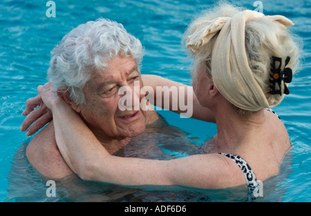 Vieux couple hugging in swimming pool Banque D'Images