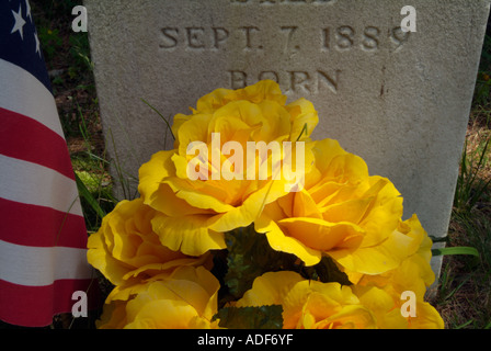 Old weathered de pierres tombales dans un cimetière de la Nouvelle Angleterre pittoresque fleurs artificielles et le drapeau américain Banque D'Images