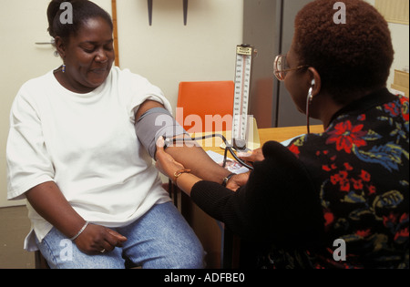 Visiteur santé prendre une femme enceinte a une tension artérielle au cours des affaires courantes les vérifier. natal Banque D'Images