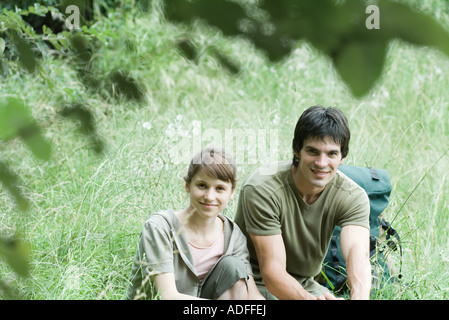 Randonnées couple resting in grass, smiling at camera Banque D'Images