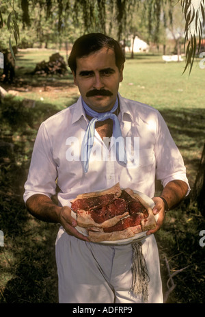 L'homme d'Argentine, gaucho, holding matières beefsteak, contact oculaire, vue de face, portrait, estancia, San Antonio de Areco, Province de Buenos Aires, Argentine Banque D'Images