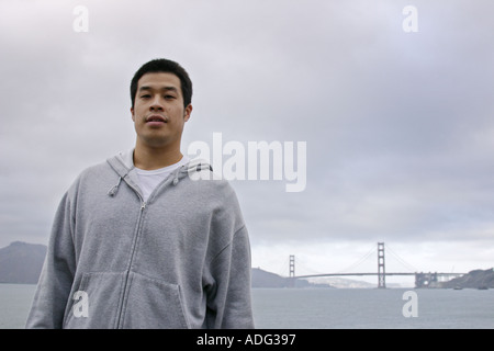 Portrait d'un jeune homme asiatique avec le Golden Gate Bridge en arrière-plan San Francisco California Banque D'Images
