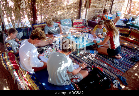 Les enfants qui apprennent la théorie de plongée PADI Junior Open Water dans un café Bédouin Dahab Sinai Egypte Mer Rouge Banque D'Images