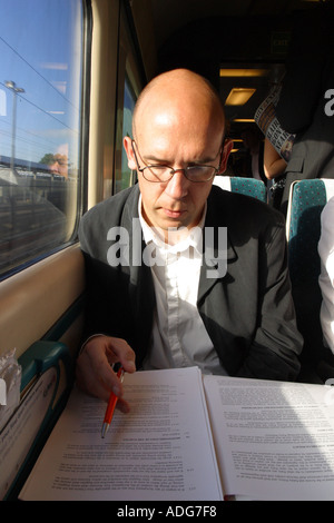 L'homme d'affaires de travail à lire des documents sur un train en préparation pour une réunion d'affaires Banque D'Images