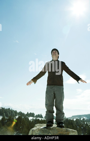 Young man standing in snowy landscape, bras dehors Banque D'Images