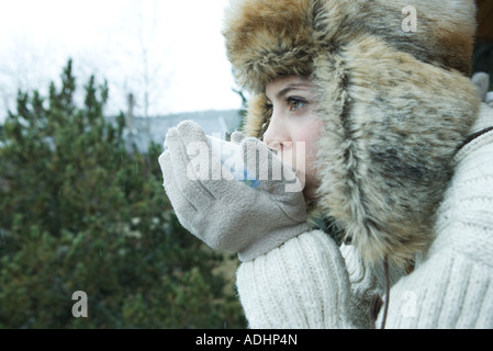 Teen girl drinking from bowl de vêtements d'hiver Banque D'Images