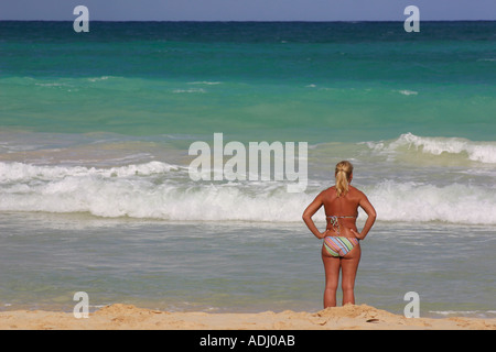 L'âge moyen woman in bikini standing on beach regarder ocean avec back to camera Banque D'Images