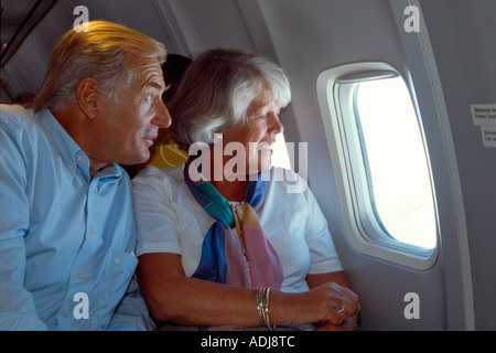 Seniorenpaar im Flugzeug aus dem Fenster schauend Banque D'Images