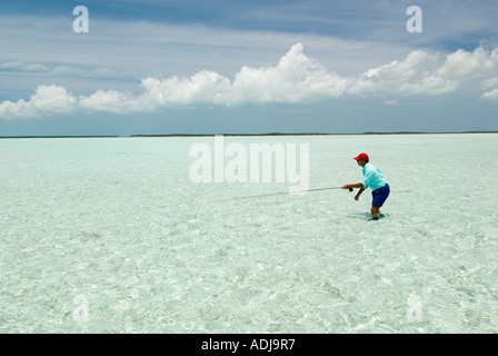 Une plus grande BAHAMA EXUMA pêcheur de mouche de patauger dans la mer vert émeraude pour moulage de Bonefish appartements Océan Atlantique Banque D'Images