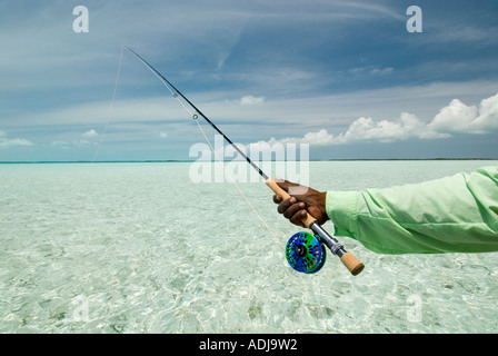 Une plus grande BAHAMA EXUMA Fly fisherman casting pour les bananes dans l'eau vert émeraude de l'Océan Atlantique Banque D'Images