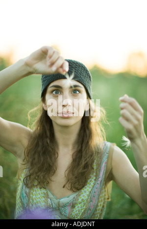 Young woman holding up graines de pissenlit, traversant les yeux Banque D'Images