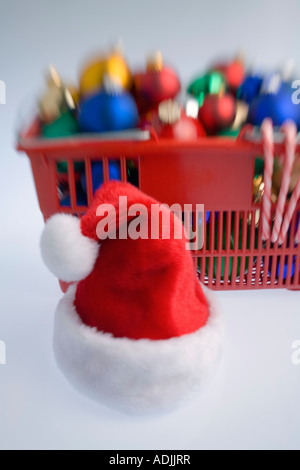 Panier rempli d'arbres de Noël ornements colorés de l'ampoule des cannes de bonbon et santa hat on white background studio portrait Banque D'Images