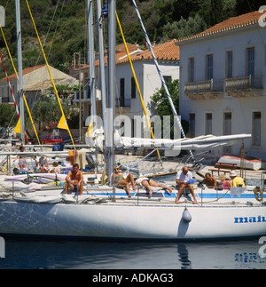 Rangée de yachts amarrés avec personnes à bord se prélasser et d'arbres et maisons derrière l'Île Ithaque Kioni dans îles grecques Grèce Banque D'Images