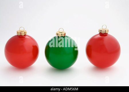 Un arbre de noël ornement rouge ampoule au milieu de deux ampoules vert dans la rangée on white background studio portrait Banque D'Images