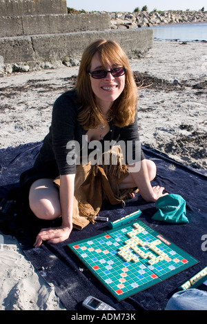 Belle jeune femme avec scrabble board sur une plage, la baie de Galway, Irlande Banque D'Images