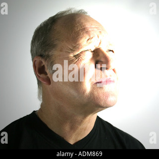 L'homme dans la soixantaine fouines à une lumière brillante au-dessus de lui Banque D'Images