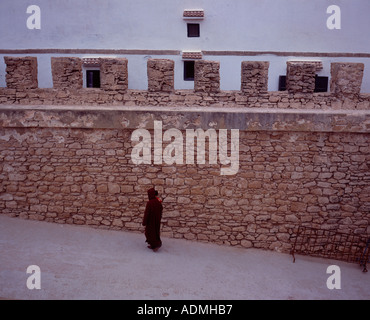 Femme vêtue d'une robe rouge à marcher le long des remparts, Médina Essaouira Maroc Banque D'Images