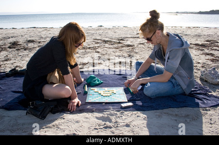 Mère et fille jouant au Scrabble sur une plage, la baie de Galway, Irlande Banque D'Images