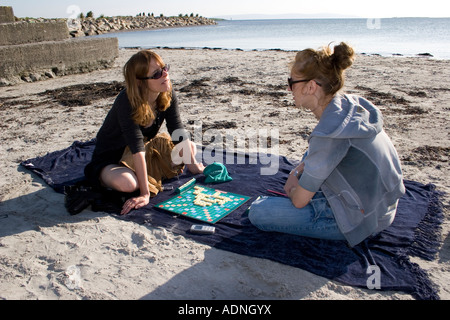 Mère et fille à l'un l'autre tout en jouant au Scrabble sur une plage Banque D'Images