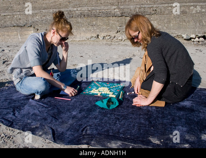 Mère et fille jouant au Scrabble sur une plage, la baie de Galway, Irlande Banque D'Images