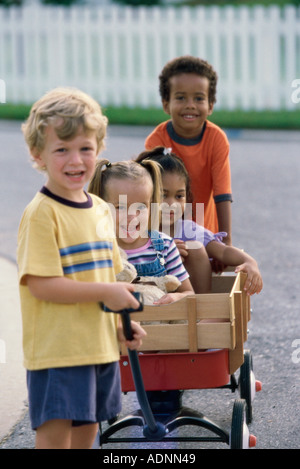 Portrait de deux garçons et deux filles jouant avec un push cart Banque D'Images