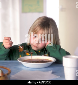 Petite fille avec un plat de soupe et pas d'appétit Banque D'Images