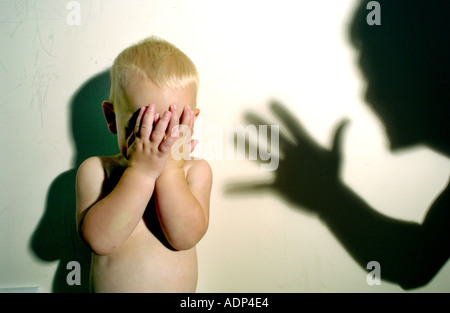 Un enfant en pleurs terrifiés menacés d'abus avec ombre d'agresseur qui pèse sur lui Banque D'Images