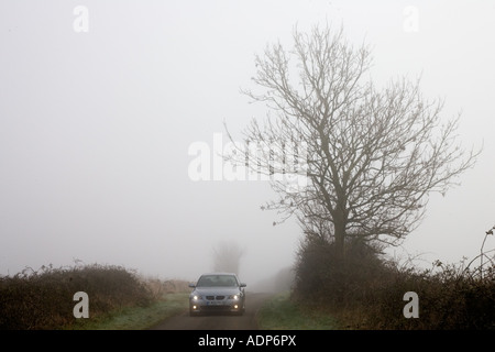 BMW Série 5 voiture conduit le long de empty country road dans les temps de brouillard Oxfordshire England Royaume-Uni Banque D'Images