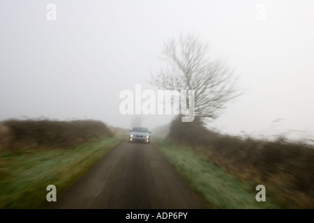 BMW Série 5 voiture conduit le long de empty country road dans les temps de brouillard Oxfordshire England Royaume-Uni Banque D'Images