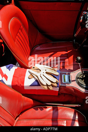 Voiture de sport Austin Healey années 60 intérieur en cuir rouge avec gants de conduite à bretelles et drapeau britannique Banque D'Images