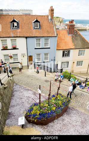 Toits de tuiles rouge ligne cottage sur forte pente pavée avec modèle de vieux gréement en premier plan, Whitby, North Yorkshire, uk Banque D'Images