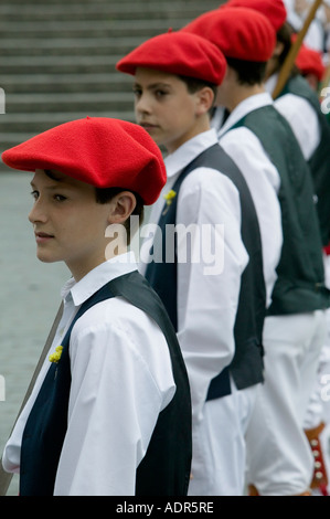 Les jeunes garçons portant des bérets rouges traditionnel debout dans une ligne lors de danses folkloriques basques Bilbao Banque D'Images