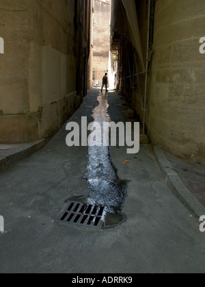 Un homme seul marche si une fuite d'eau dans une ruelle sombre Banque D'Images