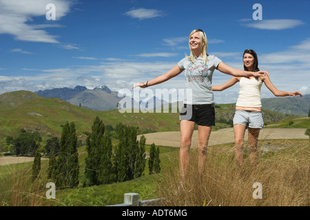 Les femmes en équilibre sur une clôture en champ avec des montagnes derrière Banque D'Images