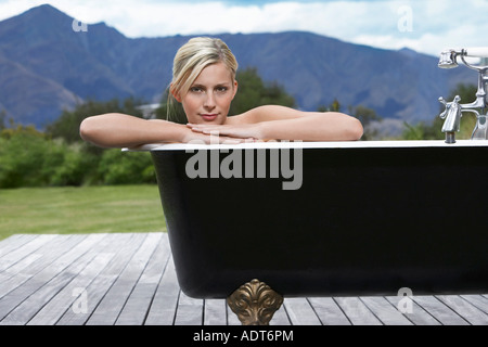 Femme dans une baignoire sur le porche de montagnes Banque D'Images