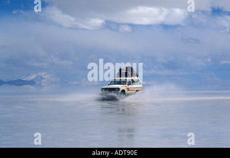 Excès de voyageurs à travers les salines de la Salar de Uyuni dans un 4x4 La fonte de la surface réfléchissante gauche Amérique Bolivie Banque D'Images