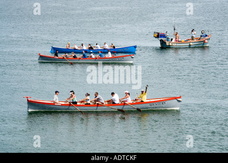 Au large de Charlestown, équipe mixte de rameurs dans trois équipes long pilote gig roats sous les ordres de starters pour courir à la mer et de retour Cornwall Angleterre Royaume-Uni Banque D'Images