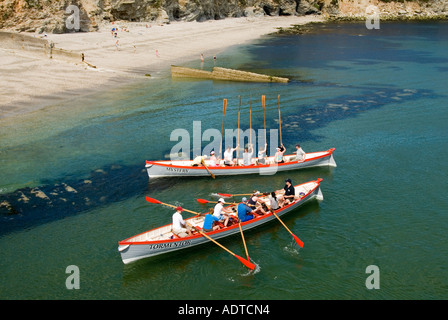 Les gagnants tiennent des oars en altitude deux équipes mixtes de grands bateaux-pilotes retournent sur le rivage de Charlestown après une course en mer et retour à Cornwall Angleterre Royaume-Uni Banque D'Images