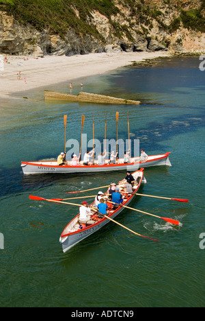 Les gagnants tiennent des oars en altitude deux équipes mixtes de grands bateaux-pilotes retournent sur le rivage de Charlestown après une course en mer et retour à Cornwall Angleterre Royaume-Uni Banque D'Images