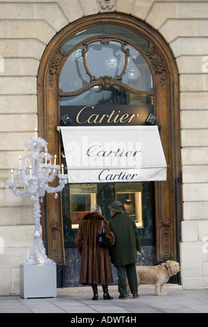 Couple élégant avec chien regarde dans la vitrine de Cartier de la Place Vendôme centre de Paris France Banque D'Images